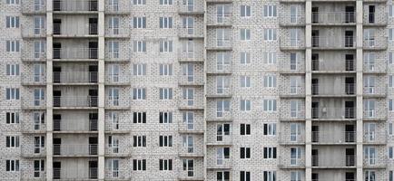 padrão texturizado de uma parede de construção residencial de pedra branca russa com muitas janelas e varanda em construção foto