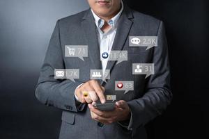 close-up empresário empurrando, tocando no smartphone com ícone de emoção virtual em fundo preto e cinza foto