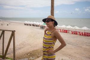 senhora na praia em combuco, brasil, encostada em poste de madeira foto