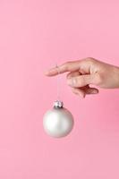 bola de ouro de vidro pendurada no dedo da mulher, decorações de natal foto