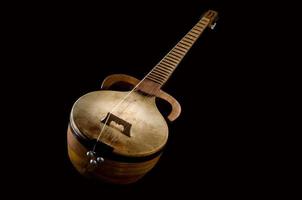 um antigo instrumento musical de cordas asiático em um fundo preto foto