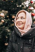 retrato de uma jovem vestida calorosamente na rua no contexto das decorações de natal em um dia frio de neve foto