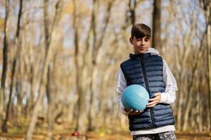 outono retrato ao ar livre de menino adolescente com bola de vôlei na floresta. foto