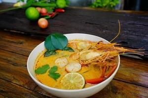 tom yum kung em um copo no chão de madeira, tom yum kung também é o prato nacional da tailândia. e é um alimento que é famoso em todo o mundo. foto