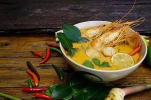 tom yum kung em um copo no chão de madeira, tom yum kung também é o prato nacional da tailândia. e é um alimento que é famoso em todo o mundo. foto