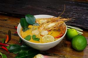 tom yum kung em um copo no chão de madeira, tom yum kung também é o prato nacional da tailândia. e é um alimento que é famoso em todo o mundo. foto