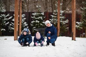 três crianças brincando em dia de inverno. irmãos com a irmã mais nova. foto