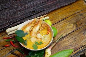 tom yum kung em um copo no chão de madeira, tom yum kung também é o prato nacional da tailândia. e é um alimento que é famoso em todo o mundo. foto