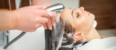 mãos de cabeleireiro lavando o cabelo da mulher foto