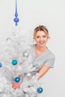 cosmetologista de pé e sorrindo perto da árvore de natal foto