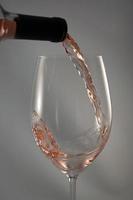 vinho rosado sendo derramado dentro de um copo