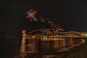 maravilhoso reflexo de fogos de artifício noturnos no mar e vista para o mar da cidade foto