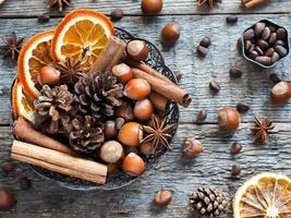 ingredientes de inverno nozes, cones, laranjas, anis estrelado de canela em uma tigela. estilo rústico foto