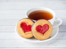 biscoitos caseiros com uma xícara de chá de coração de geléia vermelha dia dos namorados foto