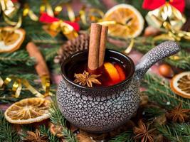 vinho quente de natal com canela, laranja e anis estrelado em uma tigela de cerâmica com decorações de inverno foto