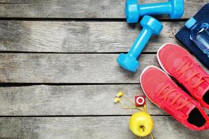 conjunto de acessórios esportivos para o conceito de fitness com equipamentos de ginástica em fundo cinza de madeira. foto