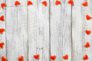 moldura feita de doces em forma de coração vermelho sobre fundo branco de madeira para dia dos namorados foto