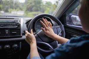 mulher empurrando a buzina enquanto dirige sentado de um carro de imprensa de volante, buzinando som para avisar outras pessoas no conceito de tráfego. foto