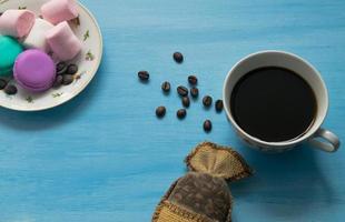 xícara de café quente com marshmallows e biscoitos sobre fundo azul. foto