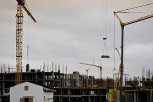 construtores masculinos trabalhando estão trabalhando no telhado de uma grande casa de estrutura monolítica, prédio e novo prédio em construção. construção do prédio no novo micro distrito da cidade grande foto