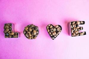 bela textura com a palavra amor para a inscrição do dia dos namorados feita de grãos de café arábica aromático natural marrom selecionado torrado, espaço de cópia robusta, configuração plana, fundo roxo rosa foto