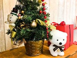 ursinho polar fofo sob a elegante linda árvore de natal do ano novo. decoração de feriado de ano novo e caixa vermelha de presente foto