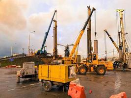 equipamento de construção no local de reparo do viaduto. o canteiro de obras é cercado de pessoas que visitam e a passagem de carros foto