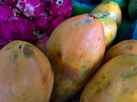 bando de mamão laranja doce. vários grandes frutos de mamão doce colocados na mesa de madeira em fundo natural para venda na loja de frutas foto