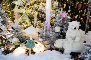 decoração de vitrine, decoração de shopping center. abeto branco artificial com guirlandas. ao lado deles estão dois filhotes de urso polar. cogumelos porcini artificiais na floresta foto