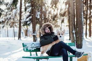 homem com cachorro corgi sentado no banco foto
