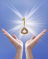 a chave para o sucesso, mão segurando a chave contra o céu azul foto