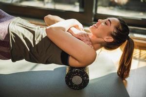 mulher fazendo exercícios com rolo de espuma em casa foto