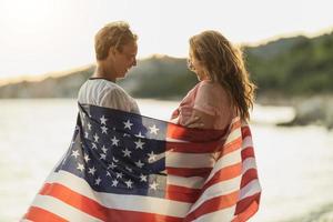 duas mulheres com bandeira nacional americana passando o dia na praia foto