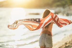 mulher com bandeira nacional americana passando o dia na praia