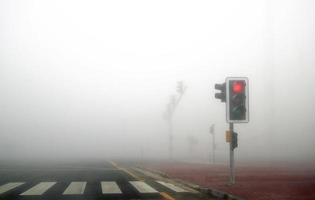 nevoeiro na estrada dubai. sinal vermelho está ligado. foto