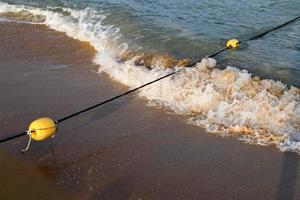 corda de cânhamo com bóias na praia da cidade foto