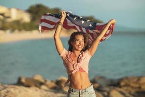 mulher com bandeira nacional americana aproveitando o dia na praia foto