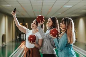 três amigas se divertindo e jogando boliche juntas foto