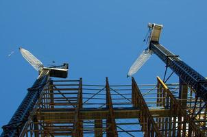 dois guindastes de construção no canteiro de obras com fundo de céu azul. foto