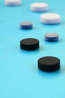 muitos comprimidos brancos, pretos e cinzas ficam na superfície azul. imagem de fundo em tópicos médicos e farmacêuticos foto