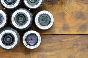 várias lentes fotográficas estão em um fundo de madeira marrom. espaço para texto foto