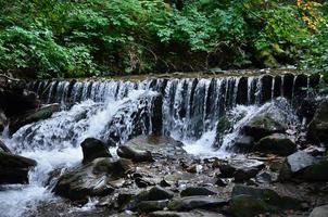 imagem aproximada de uma pequena cachoeira selvagem na forma de pequenos riachos de água entre as pedras da montanha foto