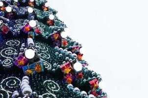 um fragmento de uma enorme árvore de natal com muitos enfeites, caixas de presente e lâmpadas luminosas. foto de um close de árvore de natal decorada com espaço de cópia