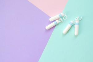 composição plana leiga com tampões menstruais em fundo pastel azul rosa e lilás foto