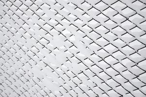 malha de metal de close-up coberta com uma espessa camada de neve nas células foto