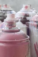 um monte de latas de aerossol sujas e usadas de tinta rosa brilhante. fotografia macro com profundidade de campo rasa. foco seletivo no bico de pulverização foto