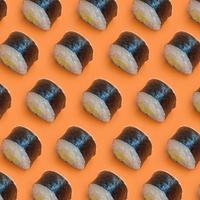 rolos de sushi preto clássico em fundo laranja brilhante foto