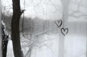 dois corações pintados em um vidro embaçado no inverno foto