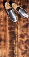 sapatos brilhantes originais em estilo disco encontram-se em uma superfície de madeira vintage feita de tábuas marrons fritas. acessório retrô de roupas da moda para discotecas e festas no estilo dos anos oitenta foto
