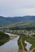 uma bela vista da vila de mezhgorye, região dos cárpatos. muitos edifícios residenciais cercados por altas montanhas da floresta e longo rio foto